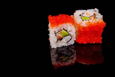 Suşi rulosu siyah arkaplanda yansımayla izole edildi.