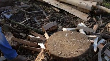 Bir adam, bir oduncu sarı bir balta ile odun yığını arka plan üzerinde bir ateş için odun doğrayın. Yakın çekim.