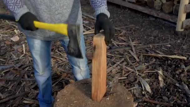 Een man, een houthakker met een gele ax, hak hout. — Stockvideo