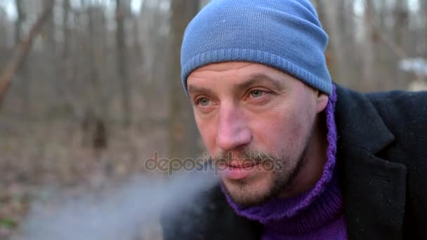 Retrato de cerca de un hombre que fuma y bebe té de una taza de metal . — Vídeos de Stock