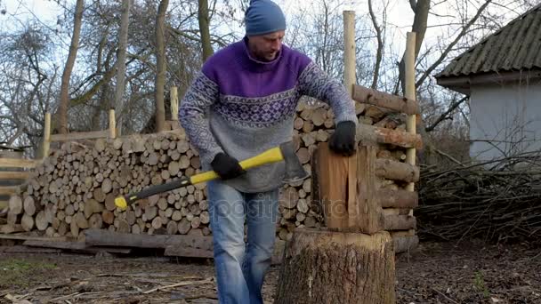 Un hombre, un leñador con un hacha amarilla, cortar madera . — Vídeos de Stock