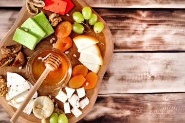 Üstten Görünüm Peynir tabağı - çeşitli peynir, bal, üzüm, kayısı, fındık ve koyu ahşap arka plan üzerinde ahşap bir gemide incir kurutulmuş.