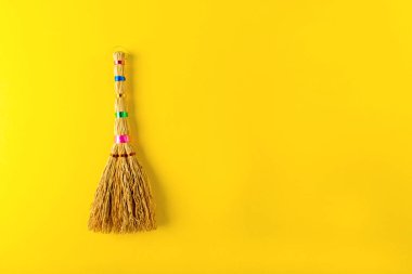 Sarı bir arka plan üzerinde süpürge.