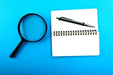 Boş boş ve kalem mavi masada olan büyüteç.