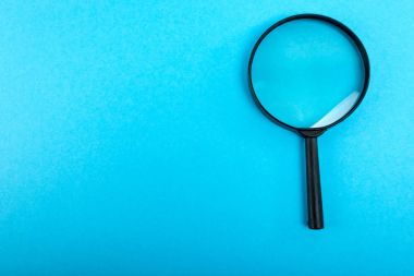 Büyüteç camı mavi masada. Üstten Görünüm.