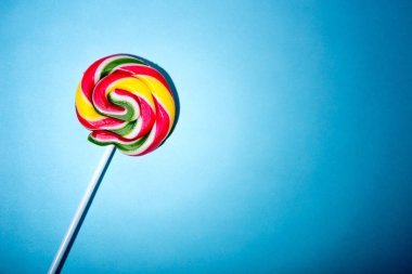 Renkli sarmal lolipop şeker çubuk üzerinde. Mavi bir arka plan üzerinde.