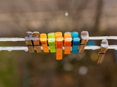 Buzla kaplı bir ipte mandallar. Plastik ve ahşap.