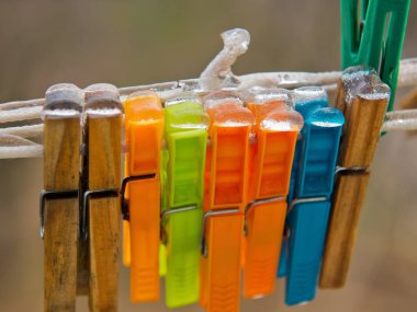 Buzla kaplı bir ipte mandallar. Plastik ve ahşap.