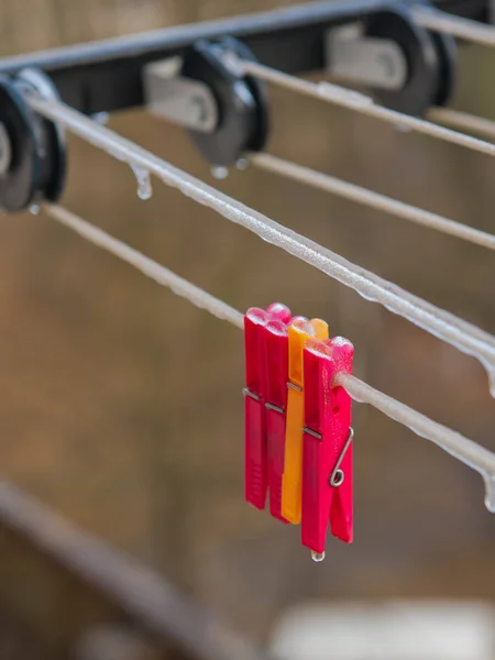 Bright plastic clothespins covered with ice. Selective focus.