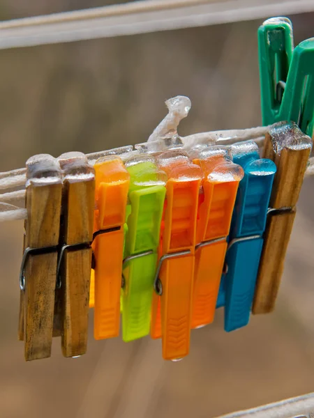 Buzla kaplı bir ipte mandallar. Plastik ve ahşap.