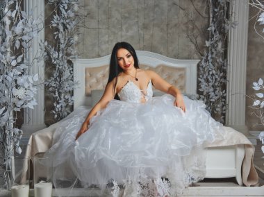 Büyük bir yatakta lüks bir elbise içinde genç gelin..