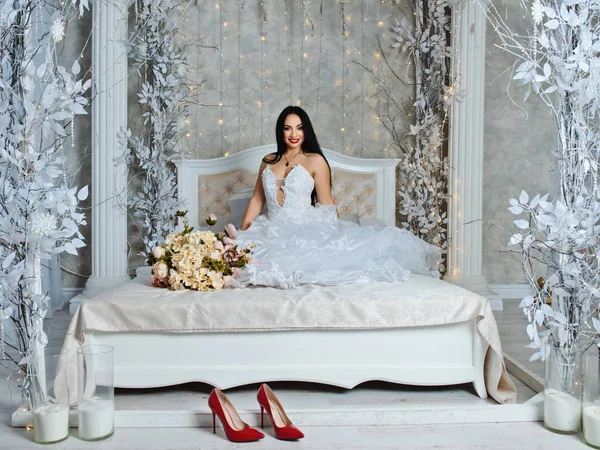 Young bride in a luxurious dress on a large bed.
