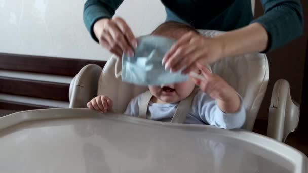 Moeder zet op haar kleine kind een medisch masker. — Stockvideo