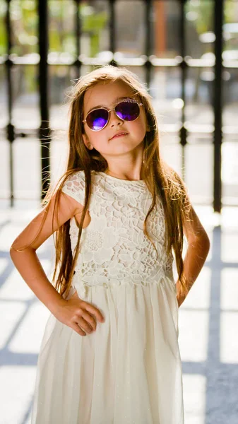 Portré Egy Fehér Ruhás Kislányról Napszemüvegben Kerítés Mellett Közelkép — Stock Fotó
