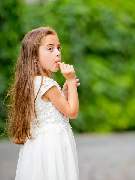 白いドレスの少女がアイスクリームを食べている — ストック写真