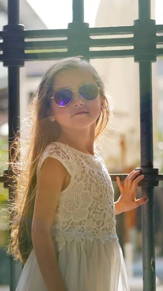 Портрет Маленькой Девочки Белом Платье Солнцезащитных Очках Возле Решетки Крупный — стоковое фото