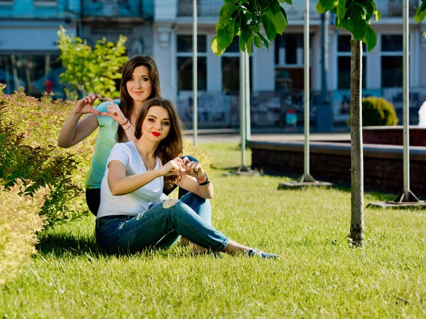 Twee Vriendinnen Jonge Meisjes Zitten Het Gazon Tonen Vingers Van — Stockfoto