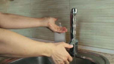 Genç bir dişinin mutfakta ellerini iyice yıkarken yakın çekimi. Coronavirus salgını önleme sabunlu suyla ellerini yıka. 