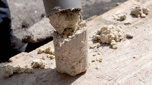 Bir tesisatçı, plastik bir kanalizasyon borusundan yağ ve enkazdan katı tortular çıkarır..