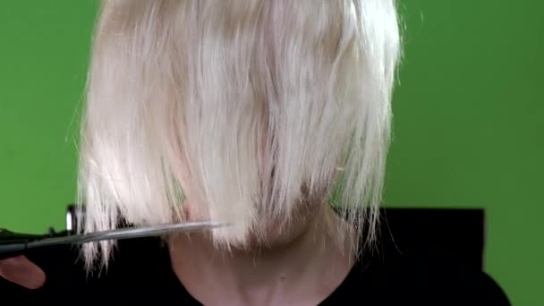 La chica se corta el pelo rubio en un cromakey. Primer plano . — Vídeo de stock