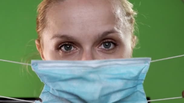 Jong blond meisje met medisch masker op groen scherm. Close-up portret op chroma key. — Stockvideo