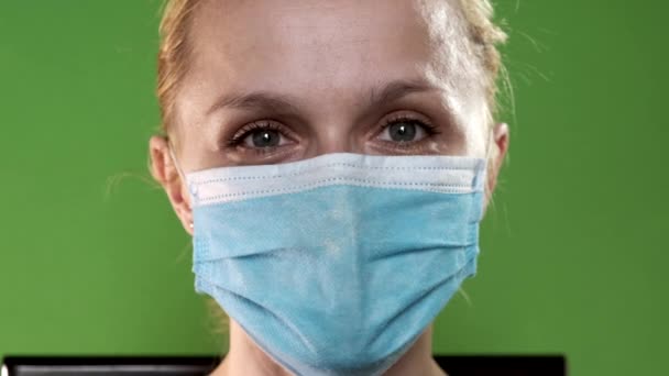 Portret van een verbaasde verpleegster met een medisch masker op een groene achtergrond. Close-up portret op chroma key. — Stockvideo