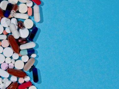 İlaç hapları, haplar ve kapsüller mavi bir arkaplan ve kopyalanmış.