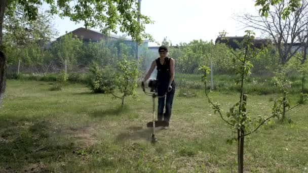 가솔린 분쇄기로 잔디를 깎는 소녀. — 비디오