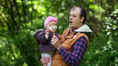 Baba ve kızı parkta karahindiba ile oynuyorlar..