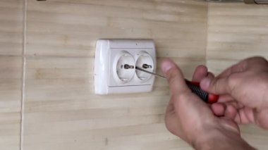 Tornavidalı erkek eller elektrik prizini tamir ediyor. Yakın plan..