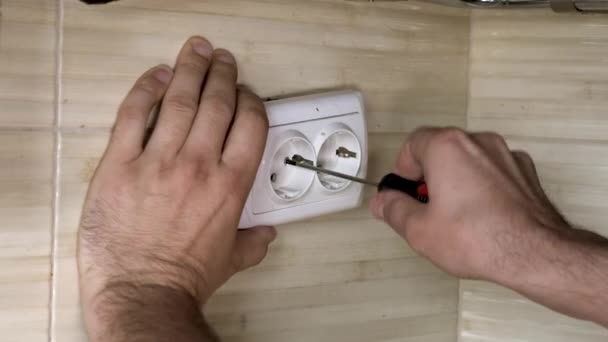 Mains masculines avec tournevis noir réparant la prise électrique blanche. Gros plan . — Video