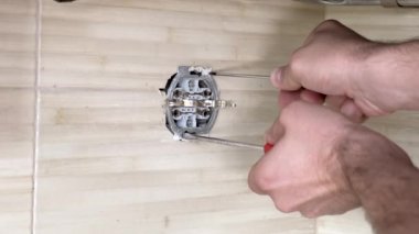Tornavidalı erkek eller elektrik prizini tamir ediyor. Yakın plan..