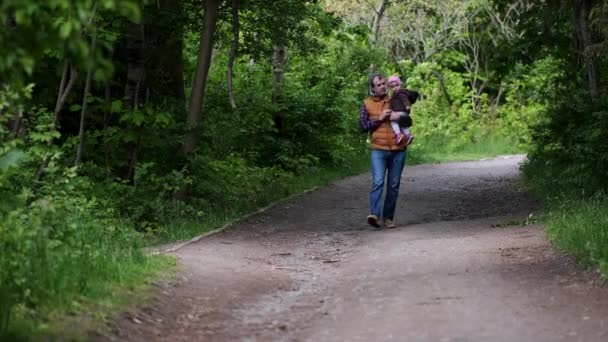 Vater mit Tochter auf dem Arm spaziert durch den Park. — Stockvideo