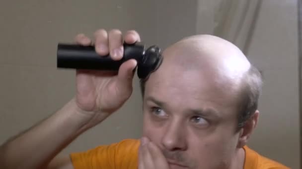 Man knipt zijn haar met een tondeuse. — Stockvideo