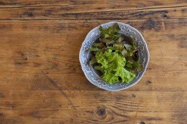 Ahşap mutfak masasında bir tabak salata ile