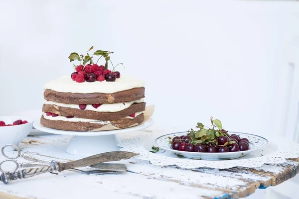 Bolo de esponja de cacau com creme de chicote e framboesas, cerejas — Fotografia de Stock