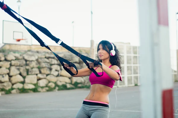 Woman training muscles with trx fitness straps — Stockfoto