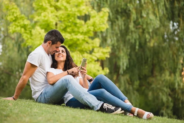 Lovers using smartphone together at city park — Stock Photo, Image
