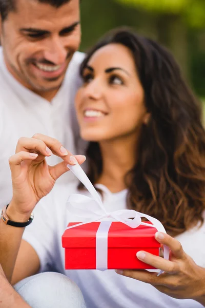 Couple of lovers openning a present in red box — Stock Photo, Image