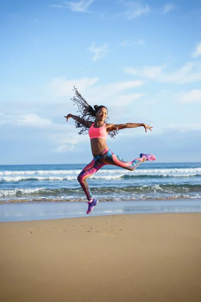 Sportig svart kvinna dansar och tränar på stranden — Stockfoto