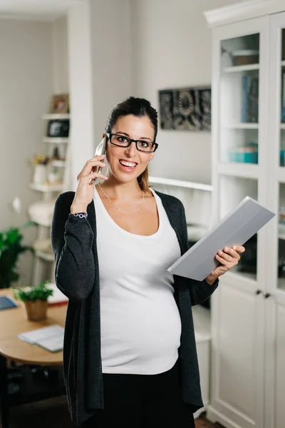Gravid kvinna som arbetar hemma med TabletPC och smartphone — Stockfoto