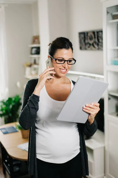 Gravid kvinna som arbetar hemma med TabletPC och smartphone — Stockfoto