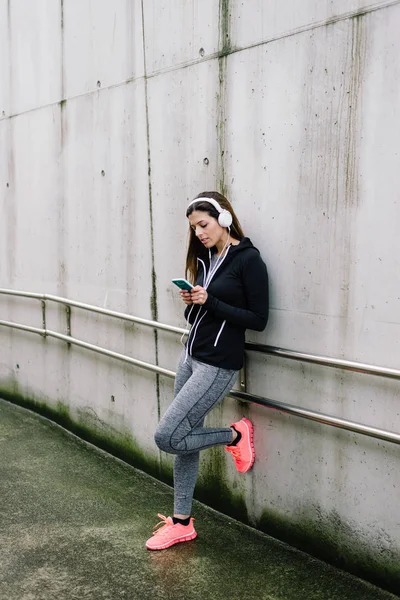 Sportowy kobieta z headhphones SMS-y na smartphone — Zdjęcie stockowe