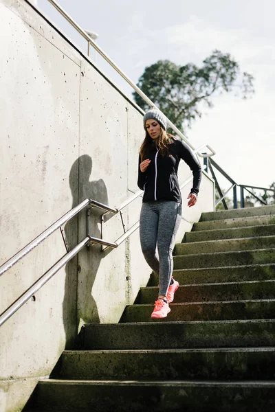 Sportliche Frau läuft in der Stadt die Treppe hinunter — Stockfoto