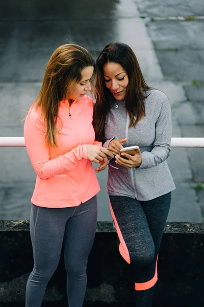 Mulheres fitness urbanas verificando treinamento com aplicativo para smartphone — Fotografia de Stock