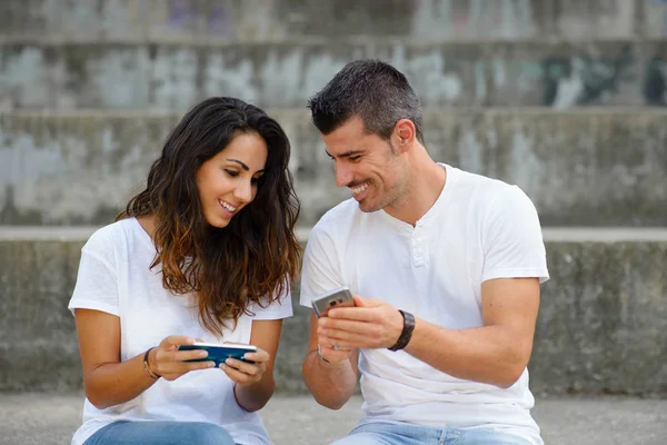 Pareja divirtiéndose y jugando con teléfonos inteligentes — Foto de Stock