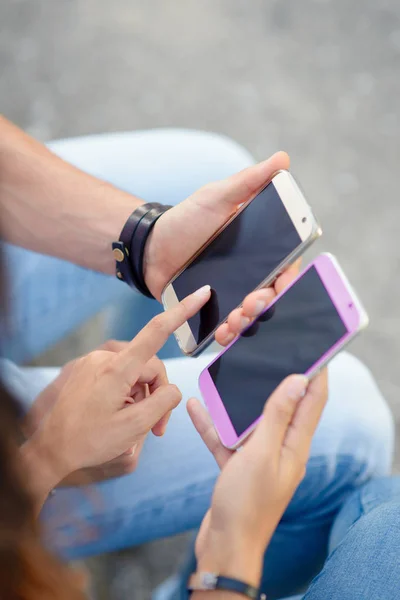 Pareja joven usando teléfonos inteligentes juntos —  Fotos de Stock