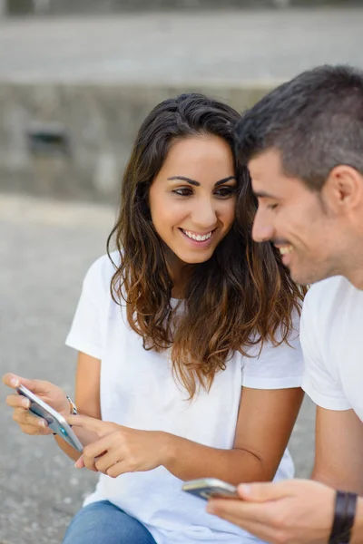 Νεαρό ζευγάρι χρονολόγηση και χρησιμοποιώντας τα smartphones μαζί — Φωτογραφία Αρχείου