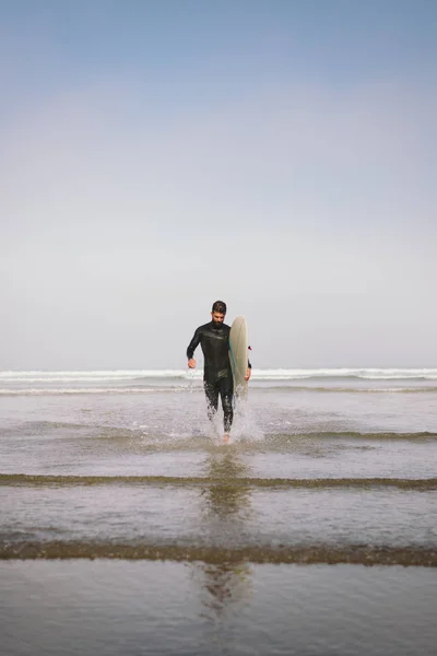 Людина в гідрокостюмі залишає воду після серфінгу — стокове фото