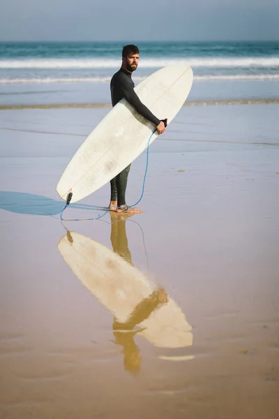 サーファー サーフィンのための海に入る前に彼のサーフボードを — ストック写真